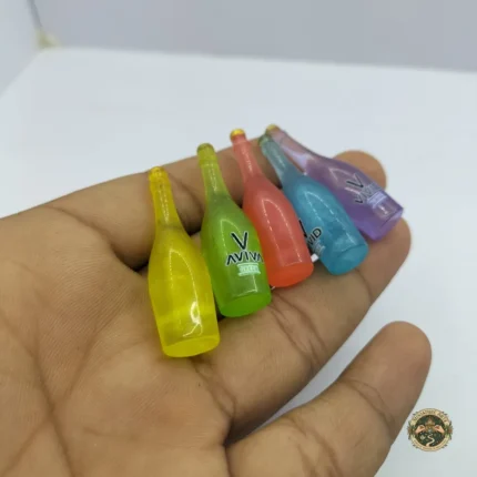 A dollhouse miniature juice bottle product with a vibrant yellow label, designed for 1:12 scale Indian grocery and kitchen dioramas.