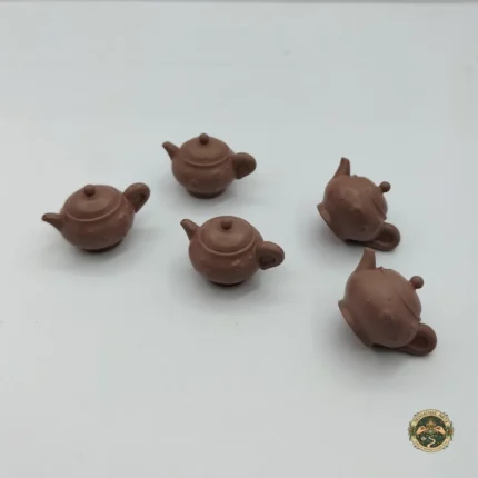 A brown miniature kettle product with a shape and handle, shown up close to highlight its design for dollhouse kitchens.