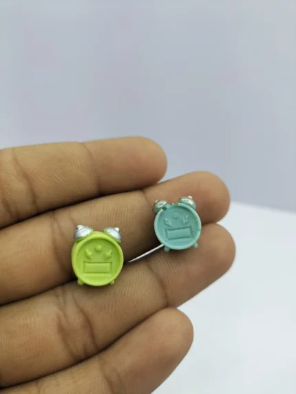 A miniature alarm clock dollhouse product with a silver twin-bell design and a white face, shown on a wooden surface.