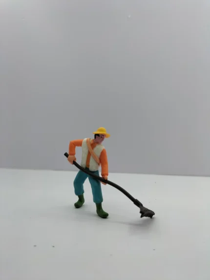 A detailed miniature farmer figurine product, hand-painted with realistic features, shown standing ready to be placed in a diorama.