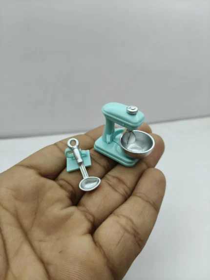 A realistic miniature kitchen hand mixer product with a classic white body and two detailed silver beaters, shown on a neutral background.