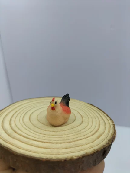 A miniature hen figurine product with hand-painted white and brown feathers, shown from a side profile on a surface.