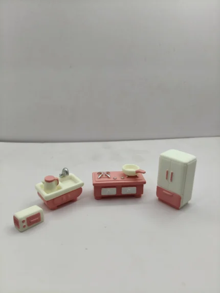 A complete pink miniature kitchen set product displayed with detailed cabinetry, a tiny stove, and small cookware accessories.