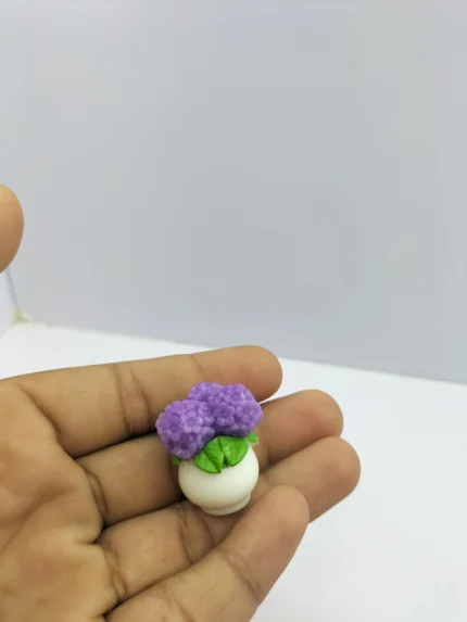 A blue dollhouse flower vase product with a slender shape, shown on a miniature wooden table to demonstrate its 1:12 scale.