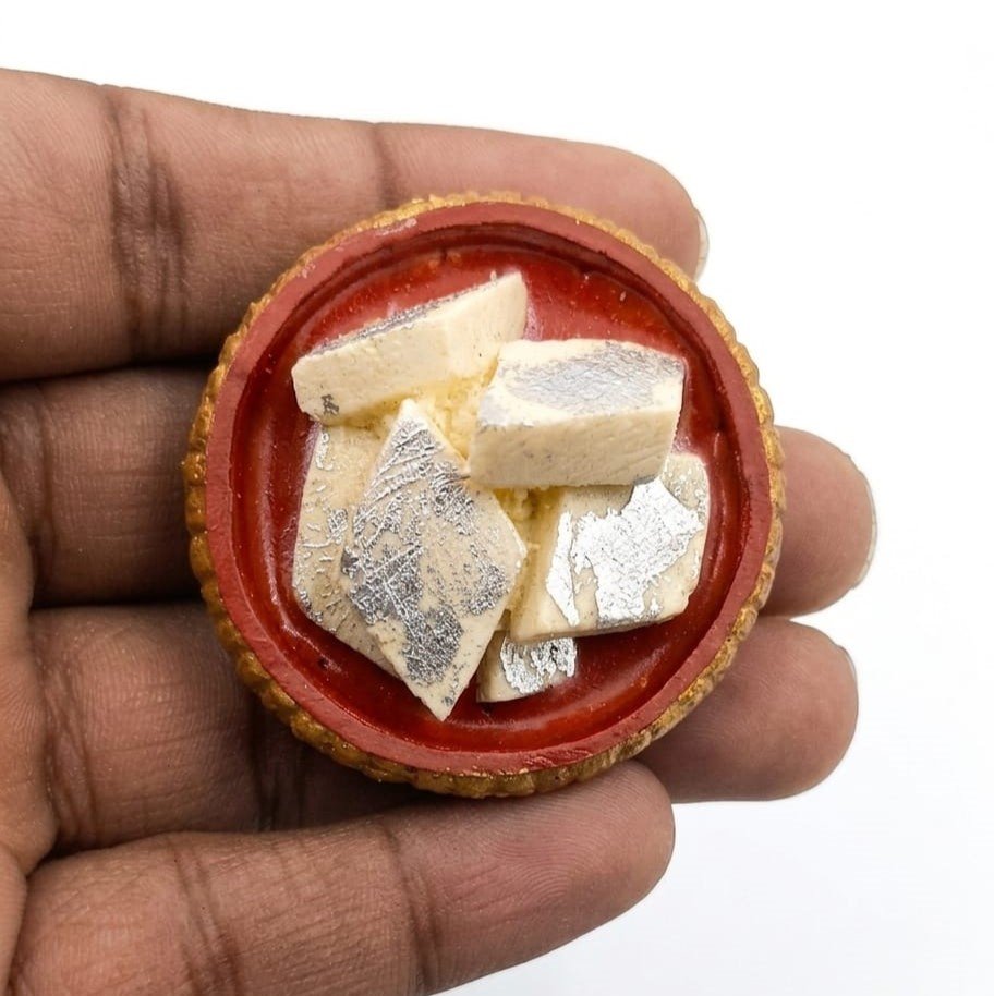 Barfi-in-Red-Katori-Miniature-Fridge-Magnet-1 A beautifully detailed miniature barfi in a red katori, presented as a charming fridge magnet product.