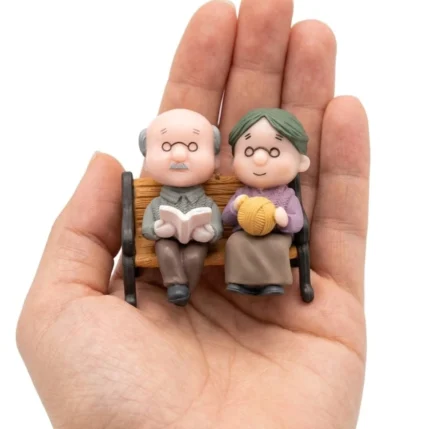 Charming elderly couple miniature figurine product on a park bench, perfect for adding warmth to any scene.
