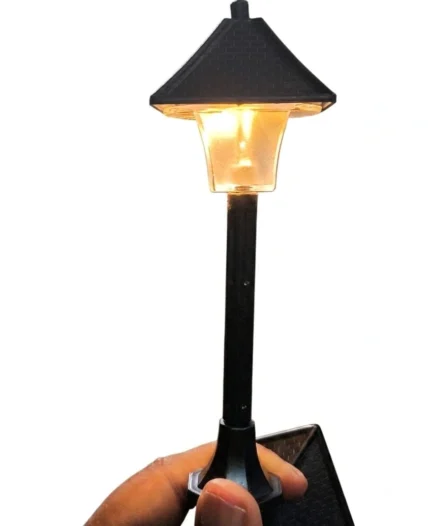 Detailed miniature street lamp post figurine with glowing LED light for dollhouse or diorama product scene.