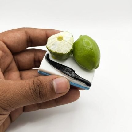 A highly detailed miniature product showing a sliced green lime with a small knife, designed as a fridge magnet.