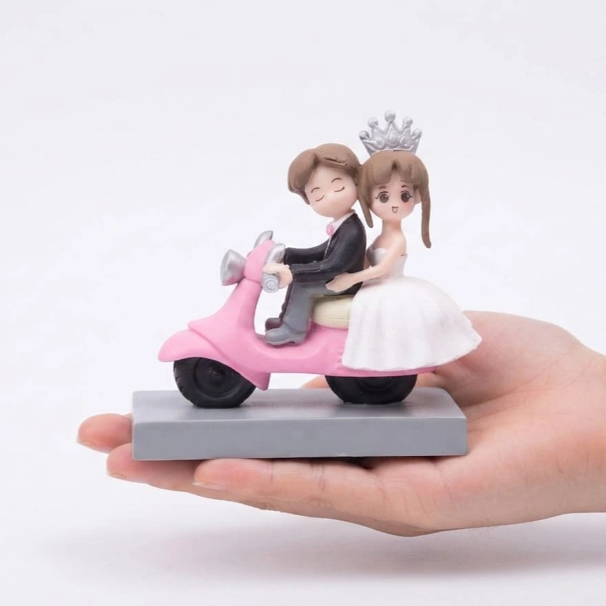 Wedding-Couple-on-Pink-Scooter-Miniature-Figurine Miniature product: Wedding couple figurine on a pink scooter, ideal for romantic decor or gifting.