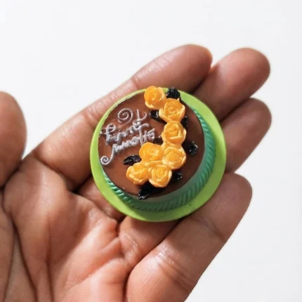 A beautifully detailed miniature chocolate cake product adorned with delicate yellow roses, perfect for display.