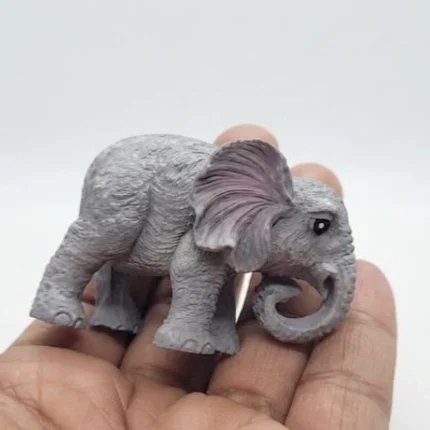 A detailed miniature grey elephant figurine product with a charming curled trunk, perfect for display.
