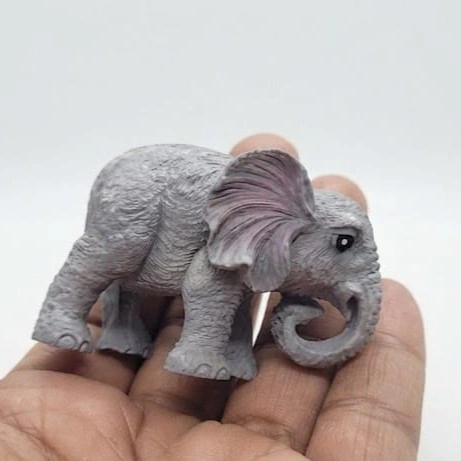Miniature-Grey-Elephant-Figurine-with-Curled-Trunk A detailed miniature grey elephant figurine product with a charming curled trunk, perfect for display.