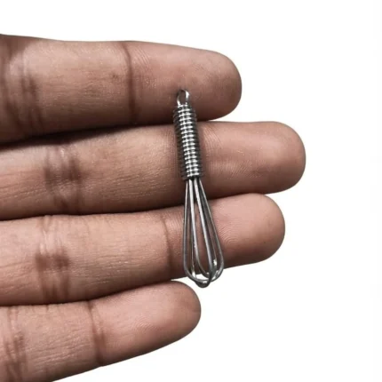 A highly detailed miniature metal wire whisk, a perfect dollhouse kitchen product, on a blurred background.