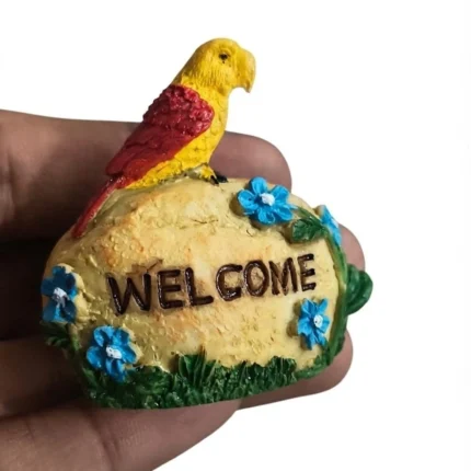 Miniature welcome stone product with a colorful parrot perched on a stone, adorned with delicate flowers.
