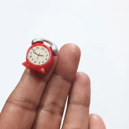 This charming red miniature alarm clock figurine is a delightful product for dollhouse decor and miniature scenes.