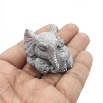 Serene sleeping baby elephant miniature figurine, a charming decorative product for nurseries or collections.