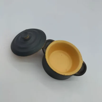 Miniature black clay cooking pot with removable lid, showcasing intricate craftsmanship of this product.
