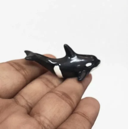 Miniature black and white dolphin figurine product, perfect for marine life display and ocean-themed decor.
