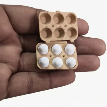 A highly detailed miniature egg carton containing six tiny white eggs, perfect as a dollhouse kitchen product.