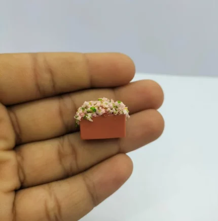 Detailed miniature pink blossom plant product in square terracotta pot, ideal for dollhouse scenes.