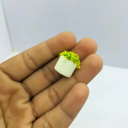 Miniature pink blossom plant in a white ribbed square pot for dollhouse decor. This product adds delicate beauty.