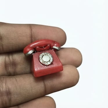 Detailed red rotary dial telephone miniature figurine product, perfect for vintage miniature scenes.