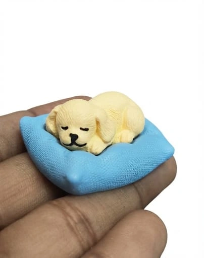 A detailed miniature product of a sleeping dog resting peacefully on a soft, plush cushion, perfect for display.