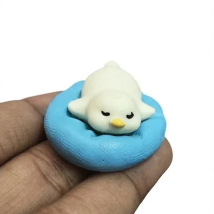 Charming sleeping penguin miniature figurine on blue cushion, a delightful product with detailed craftsmanship.