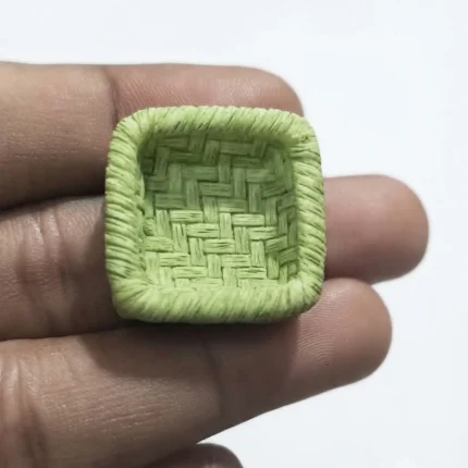 Miniature green woven basket, a beautifully crafted product for dollhouse enthusiasts and collectors.