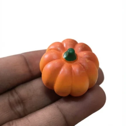 Miniature orange pumpkin figurine for dollhouse displays and fall decor. This product adds a festive touch.