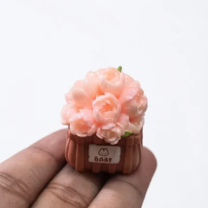 Miniature pink peony flower in a baby basket. This product adds delicate charm to dollhouse scenes.