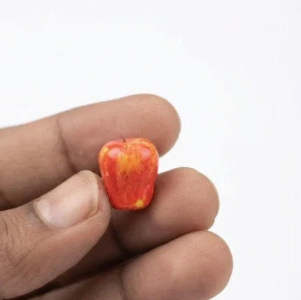 Highly detailed miniature red apple figurine for dollhouse scenes or diorama displays, a realistic product.