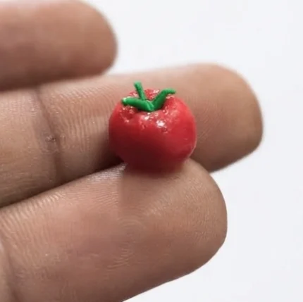 Charming miniature red tomato figurine product, ideal for dollhouse scenes or tiny displays, adding garden realism.