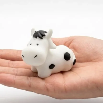 A detailed miniature black and white cow figurine product, perfect for collectors and home decor enthusiasts.