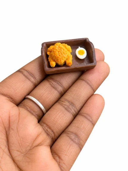 Miniature breakfast food product: fried chicken drumstick and sunny-side-up egg on a tiny plate.