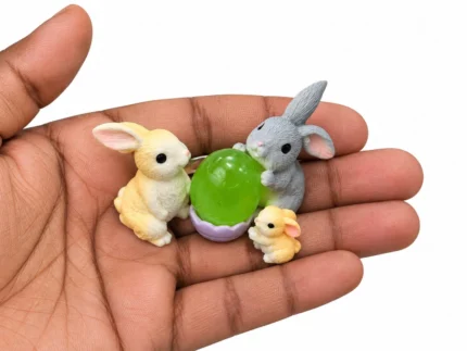 Charming miniature rabbit pair product with a vibrant green Easter egg, ideal for dollhouse scenes.