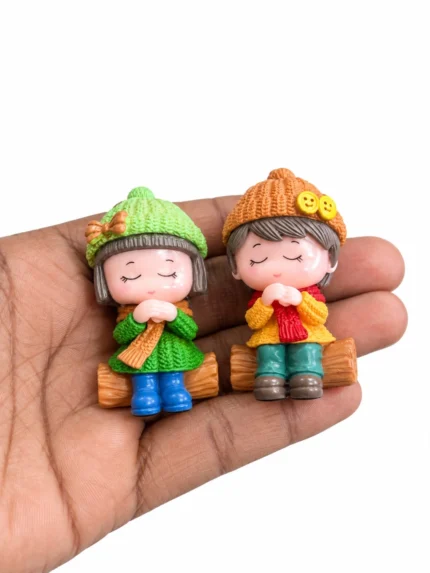A delightful miniature product featuring two winter kids sitting on a log, perfect for festive holiday displays.